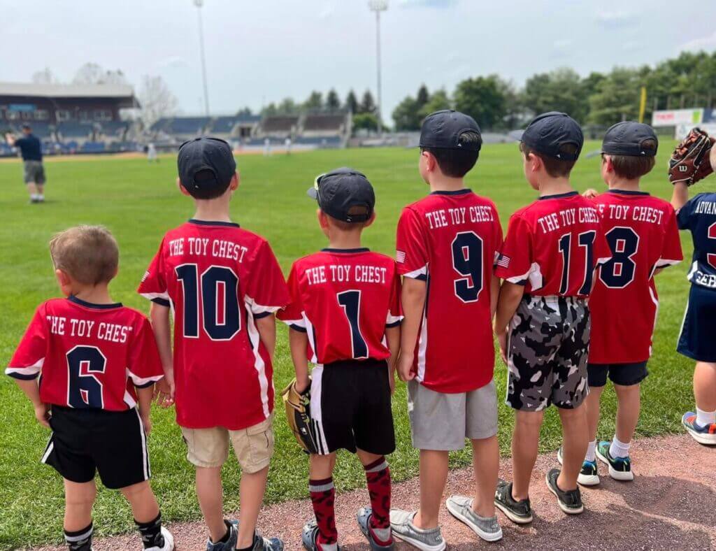 Youth baseball players in red jerseys lined up on a field