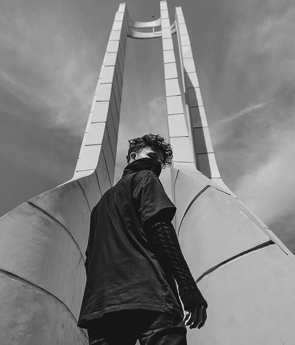 Black-and-white photo of a person walking toward a tall building